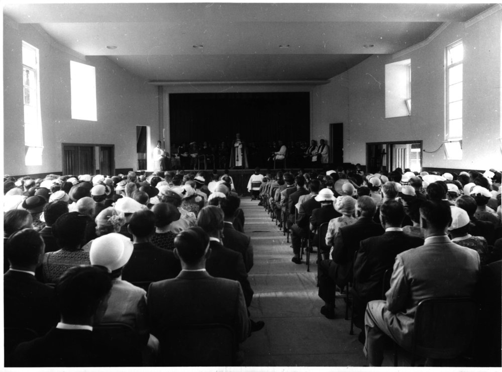 Church hall interior with a gathering and clergy on stage