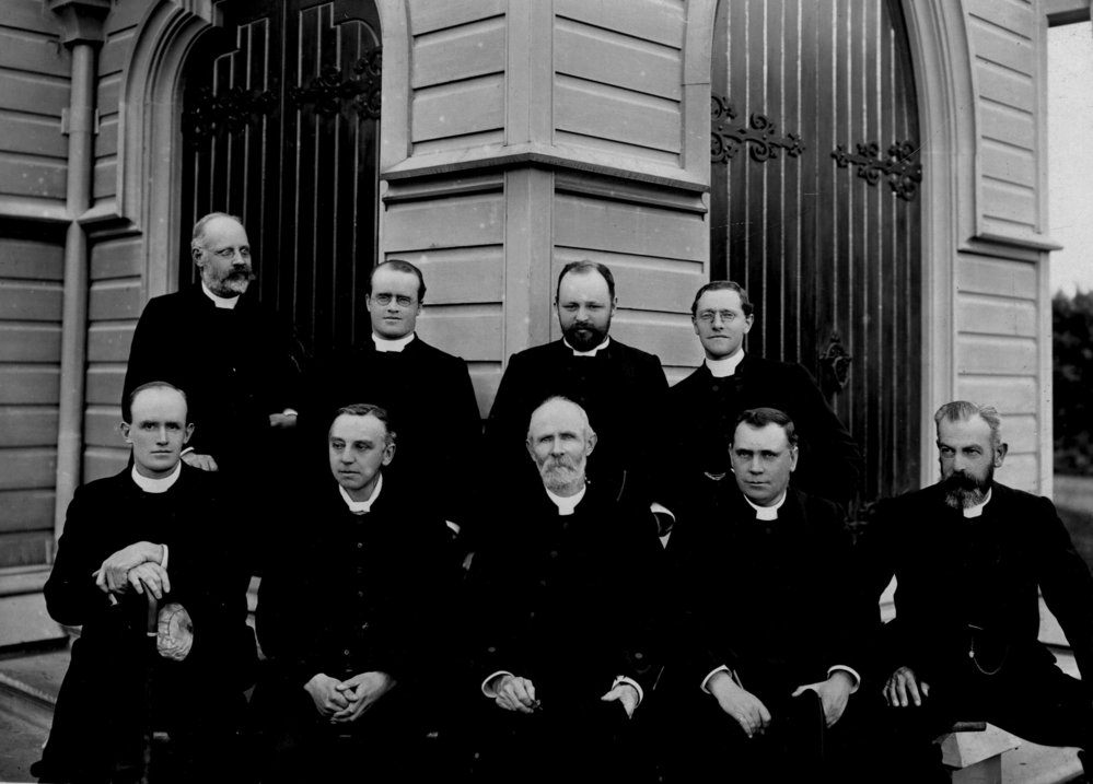 Diocese of Auckland group of clergy photographed outside of a wooden church
