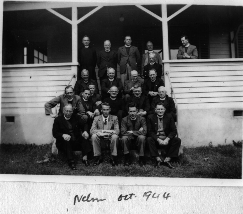 Clergy outside large wooden villa