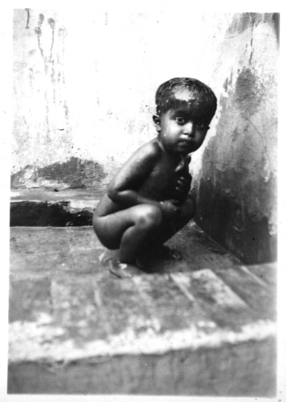 A little Mohammedan boy cooling himself under the tap in the hospital compound
