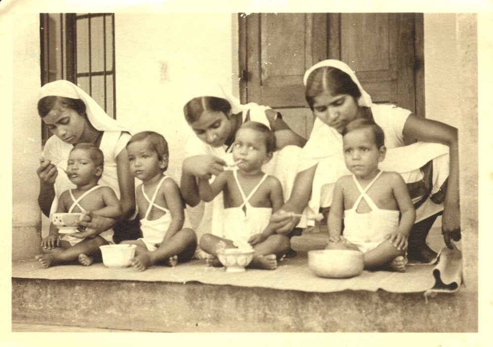 Three Indian nurses feeding children