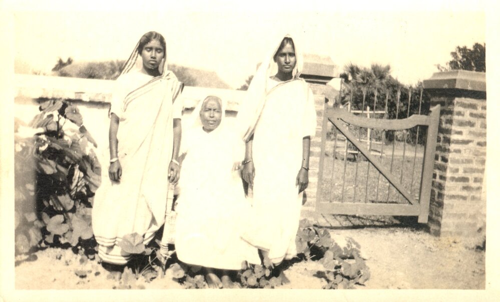 Three Indian women. 1 sitting, 2 standing. 