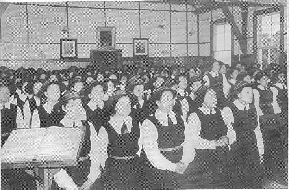 Hukarere students attending a worship service, wearing hats and gym tunics.  Bible open on the lecturn in foreground of the photos