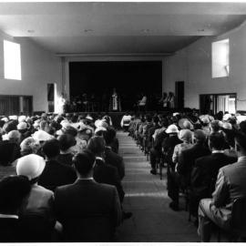 Church hall interior with a gathering and clergy on stage