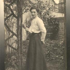 Portrait of Dora in a garden posing by a trellis.  