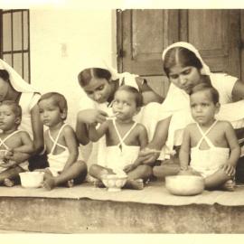 Three Indian nurses feeding children