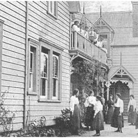 Hukarere School buildings with students in dark skirts and white shirts, with a tennis raquet