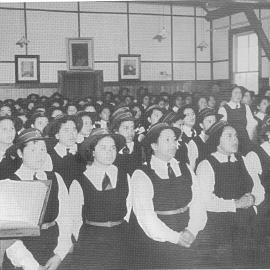Hukarere students attending a worship service, wearing hats and gym tunics.  Bible open on the lecturn in foreground of the photos